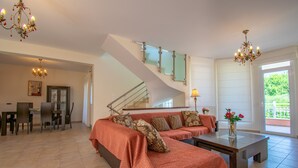 Amplia sala de estar con un conjunto de sofás, una mesa de comedor y una escalera.
