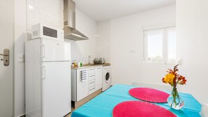 A compact kitchen with a refrigerator, microwave, stove, and washing machine.