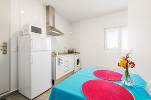A compact kitchen with a refrigerator, microwave, stove, and washing machine. - Modern Studio Apartment "La Higuera 1" with Wi-Fi and Air Conditioning (Cadiz)