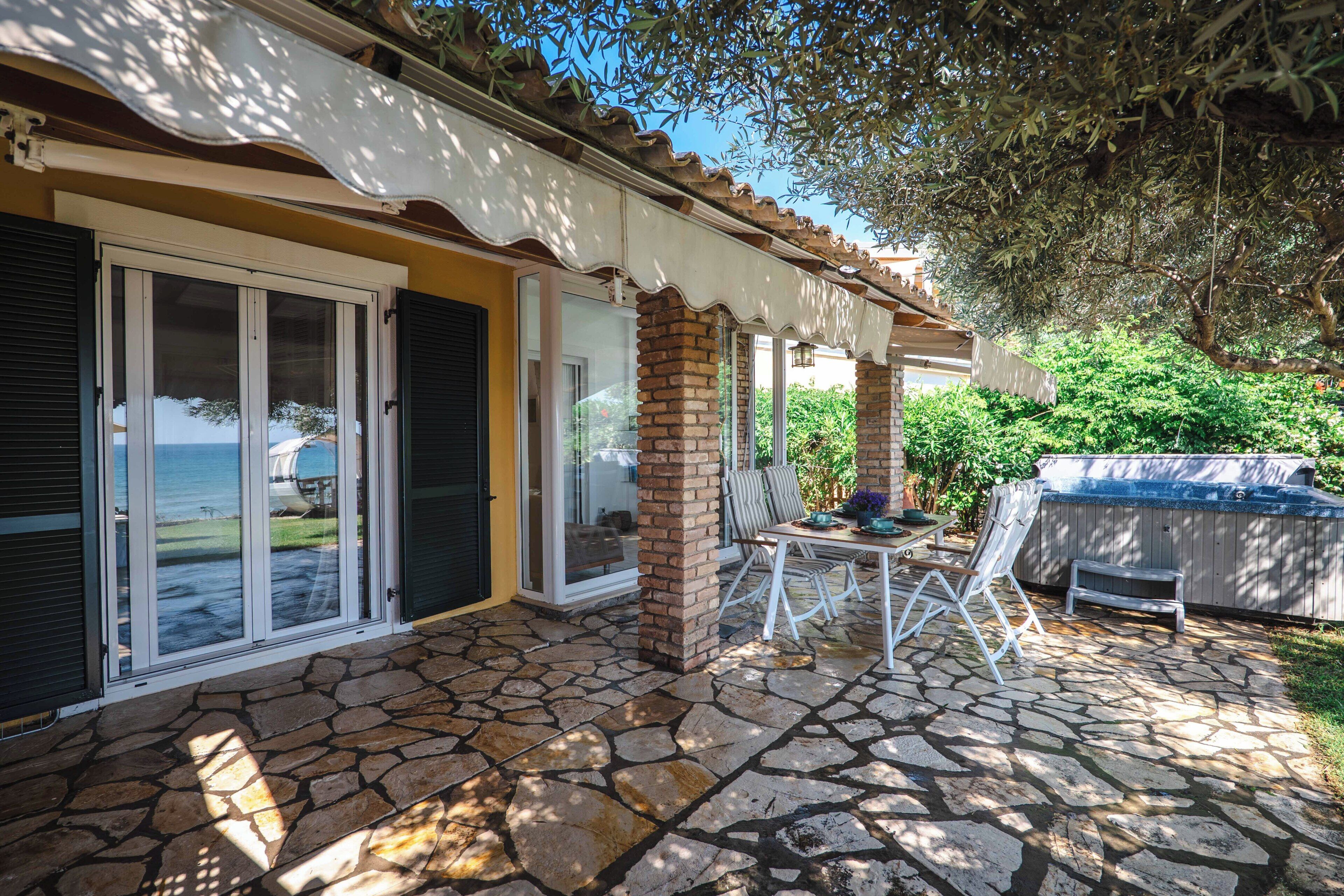 A patio with stone flooring, a table, chairs, and a barbecue grill.