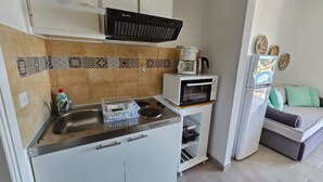 A compact kitchen with a microwave, coffee maker, and a small refrigerator.
