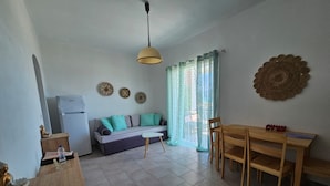 A compact living space with a kitchenette, a sofa, a dining table, and a ceiling light.