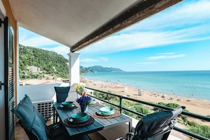 Un balcon avec une table dressée pour le dßner, offrant une vue sur une plage et la mer.