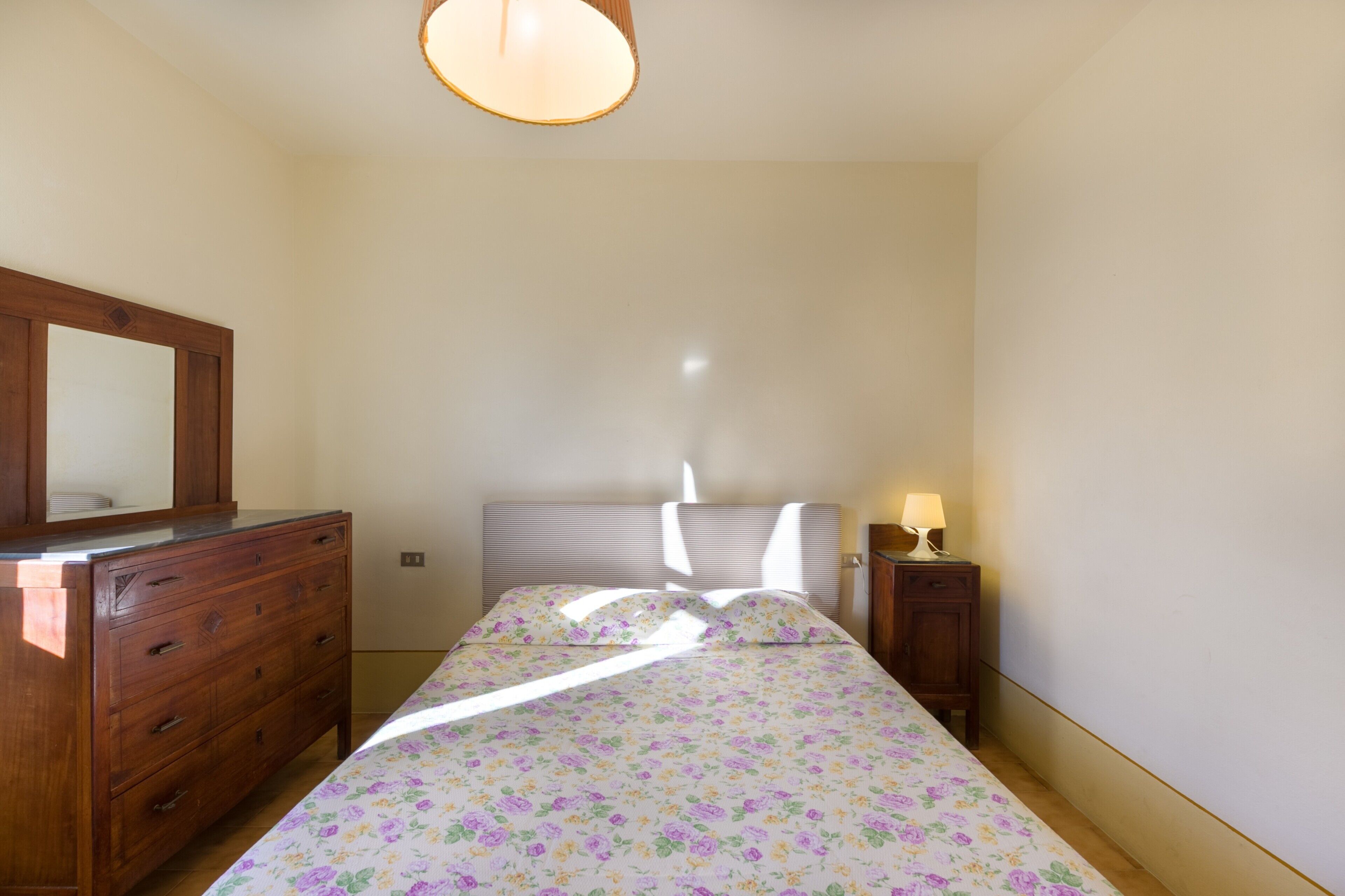 Ein Schlafzimmer mit Bett, Schminktisch, Nachttisch und Spiegel.