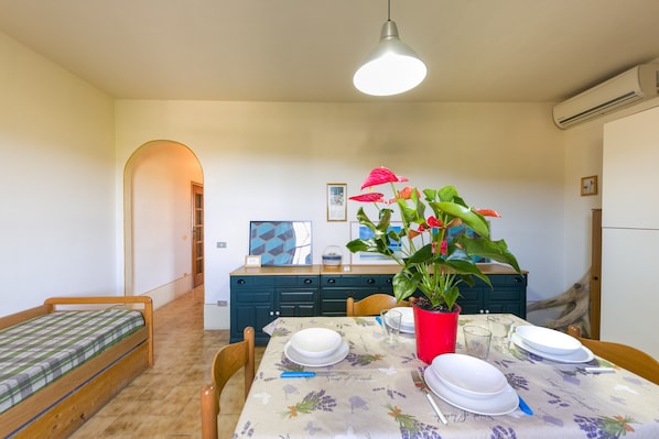 A dining area with a table set for four, a bench, a potted plant, and a ceiling light.