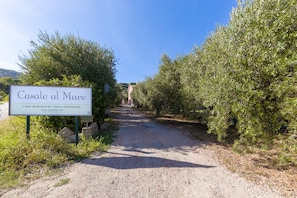A gravel path leading to a sign for Casale al Mare with contact information.