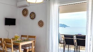 A dining area with a table, chairs, and a TV on the wall. - Corfu Glyfada Menigos Resort No01 (Corfu)