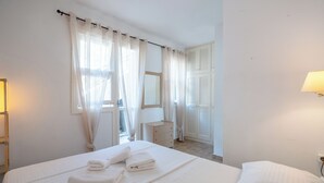 A hotel room with a bed, a dresser, a mirror, and a window with curtains. - Corfu Glyfada Menigos Resort 24 (Corfu)