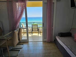Una habitación con balcón, sofá, mesa y sillas.