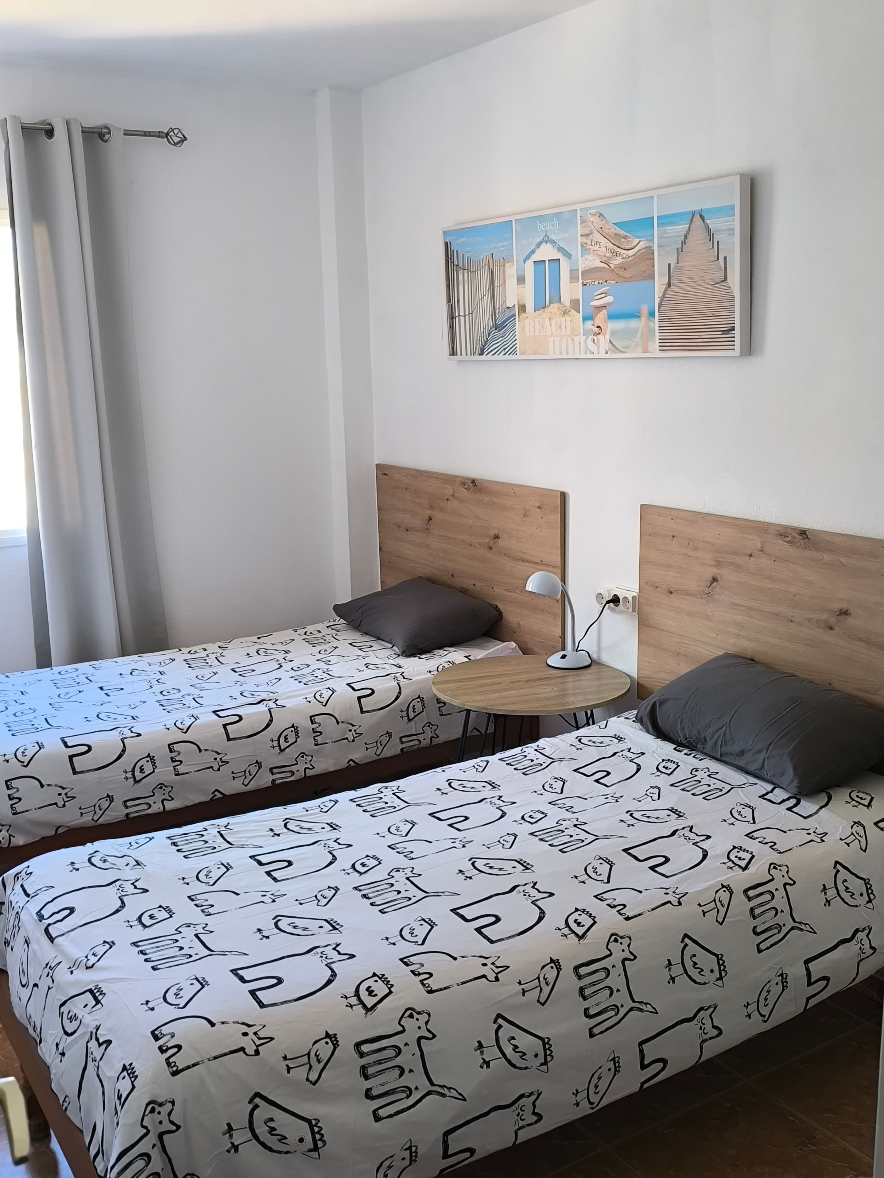Una camera d'albergo con due letti, un tavolino rotondo e un quadro appeso al muro.