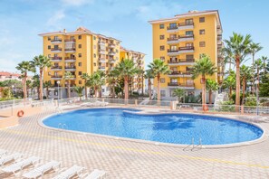 Ein Hotel mit Schwimmbad, umgeben von Palmen und einer gefliesten Terrasse.