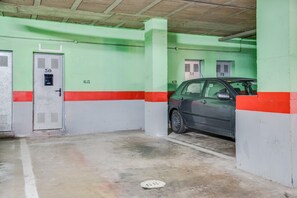 A parking garage with numbered parking spaces, concrete floors, and green walls. - Superior Beachfront Apartment with Pool, Balcony, Sea Views & Wi-Fi; Parking Available (Candelaria)