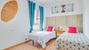 A bedroom with two beds, a wooden wall decoration, a 'ENJOY' sign, and a striped wall panel. - Superior Beachfront Apartment with Pool, Balcony, Sea Views & Wi-Fi; Parking Available (Candelaria)