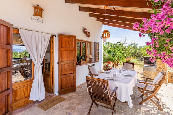 An open wooden door leading to a dining area with a table set for two, a hanging lantern, and a view of greenery outside. - Fantastic Finca Son Mulet with Pool, Aircondition, Garden, Terrace & WLAN; Parking Available (Llubí)