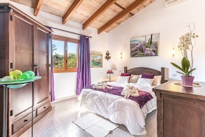 A bedroom with a bed, a nightstand, a dresser, a window with curtains, and a wall-mounted lamp. - Fantastic Finca Son Mulet with Pool, Aircondition, Garden, Terrace & WLAN; Parking Available (Llubí)