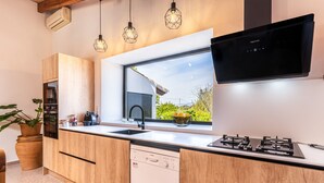 Cozinha moderna com armários de madeira, máquina de lavar louça Bosch, fogão a gás e uma janela ampla com vista para o verde.