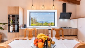 Cozinha moderna com uma janela grande, armários de madeira e uma fruteira sobre a mesa.