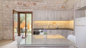 A modern kitchen with stone walls, a glass island, and white cabinetry.