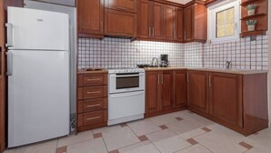 Una cocina con armarios de madera, un refrigerador blanco, un horno y un salpicadero de azulejos.