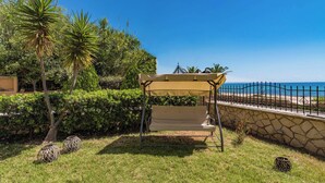 Un espacio de estar al aire libre con techo, pared de piedra y vista al mar.