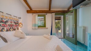 A bedroom with a bed, a wall tapestry, a window with curtains, and a view through an open door. - Dream Villa with Terrace, Wi-Fi, Air Conditioning and Shared Pool (Porto Rotondo)