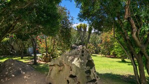 A large rock formation in a garden with trees and a clear sky. - Dream Villa with Terrace, Wi-Fi, Air Conditioning and Shared Pool (Porto Rotondo)