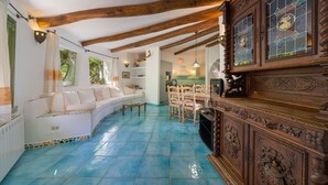 A room with a white sofa, wooden ceiling beams, a tiled floor, and a wooden cabinet with intricate carvings. - Dream Villa with Terrace, Wi-Fi, Air Conditioning and Shared Pool (Porto Rotondo)