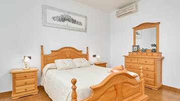 Un dormitorio con una cama de madera, mesitas de noche, un aparador y un espejo.