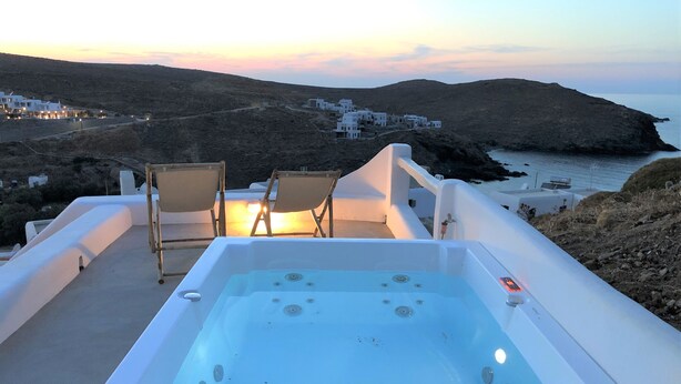 Un bain à remous avec deux sièges, offrant une vue sur un paysage côtier avec des bâtiments en arrière-plan.