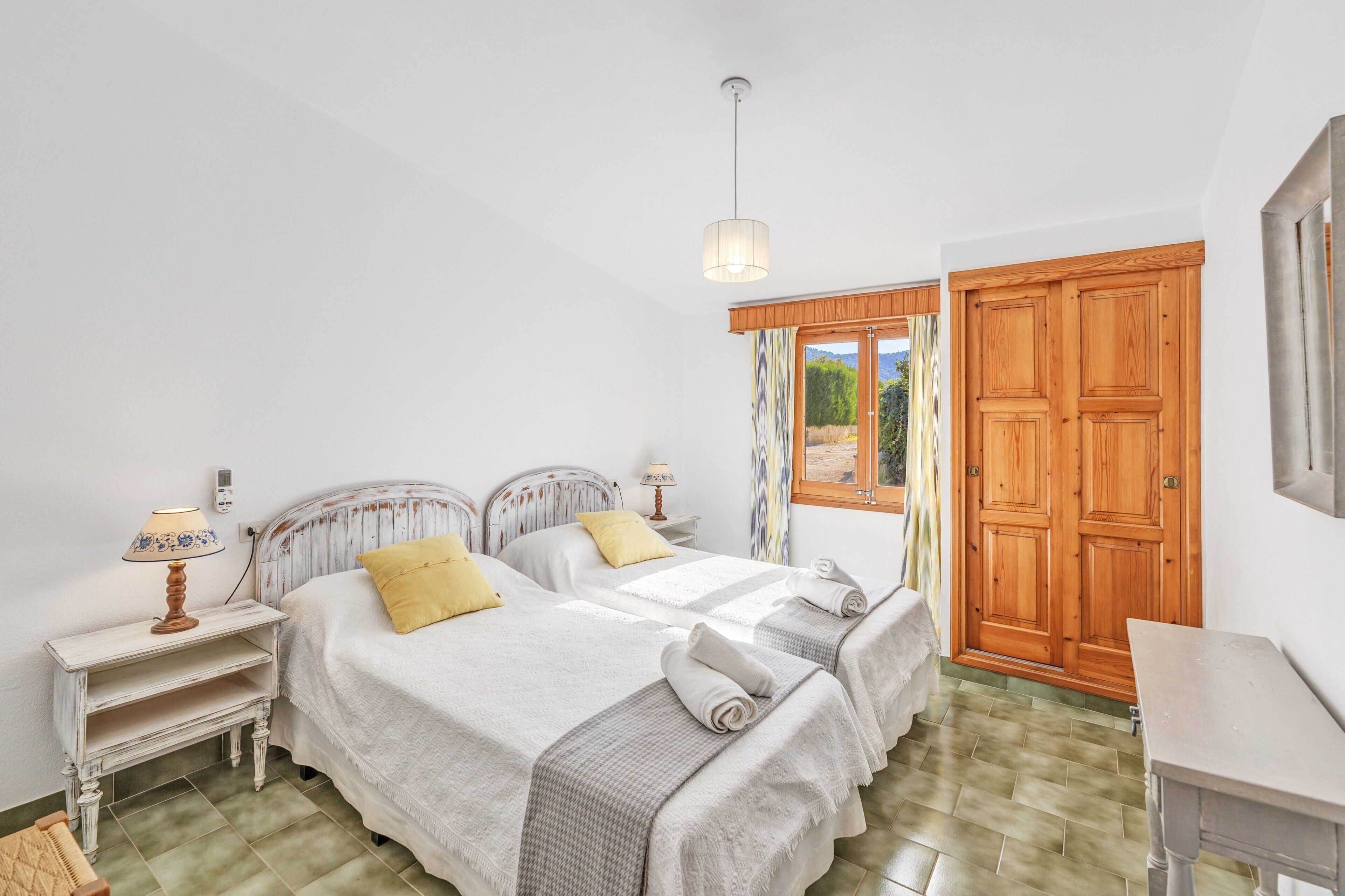 Una camera da letto con due letti, un armadio in legno, una scrivania e una finestra con tende.