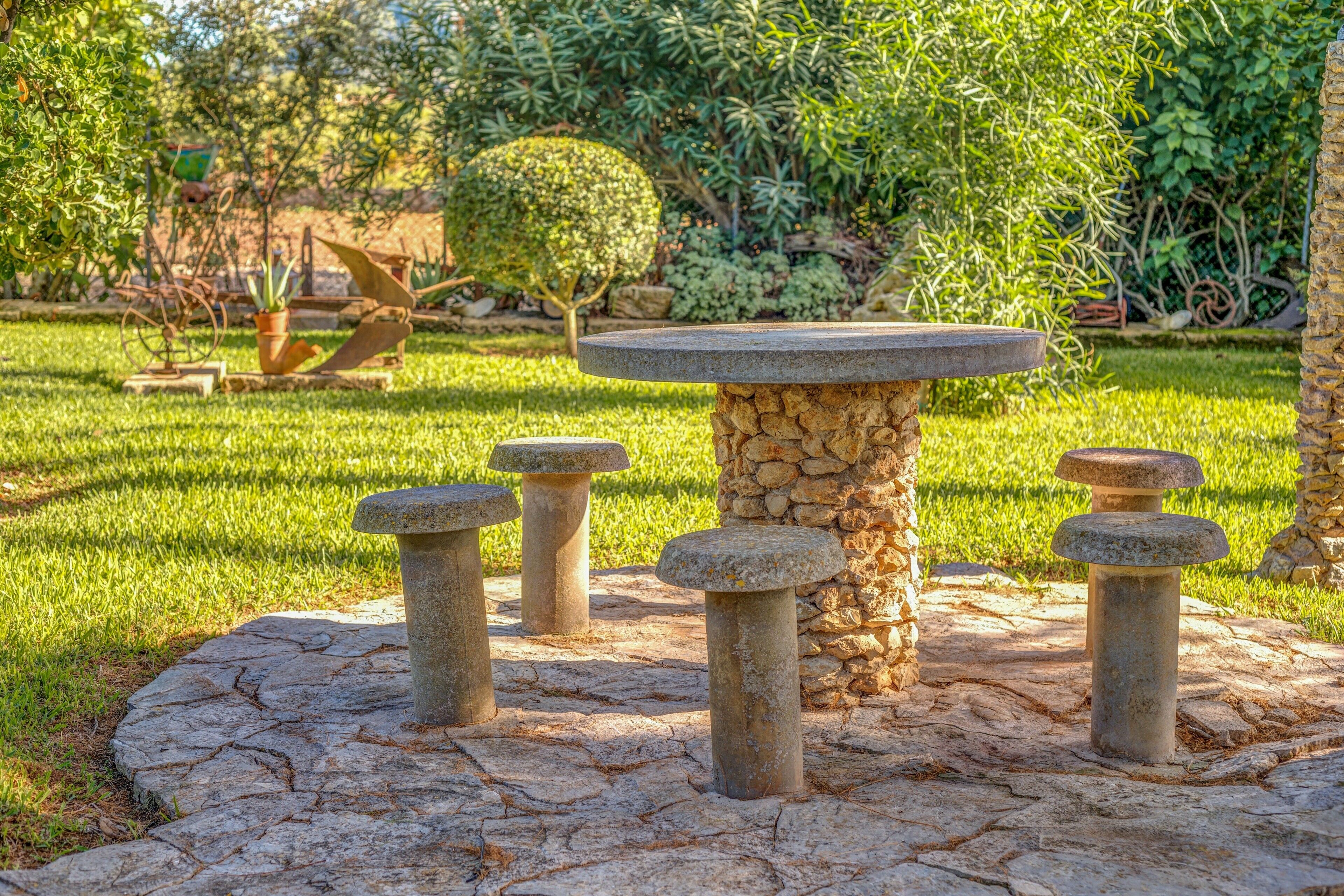 Une table en pierre, dotée d’un plateau circulaire, et entourée de quatre piédestaux en pierre.