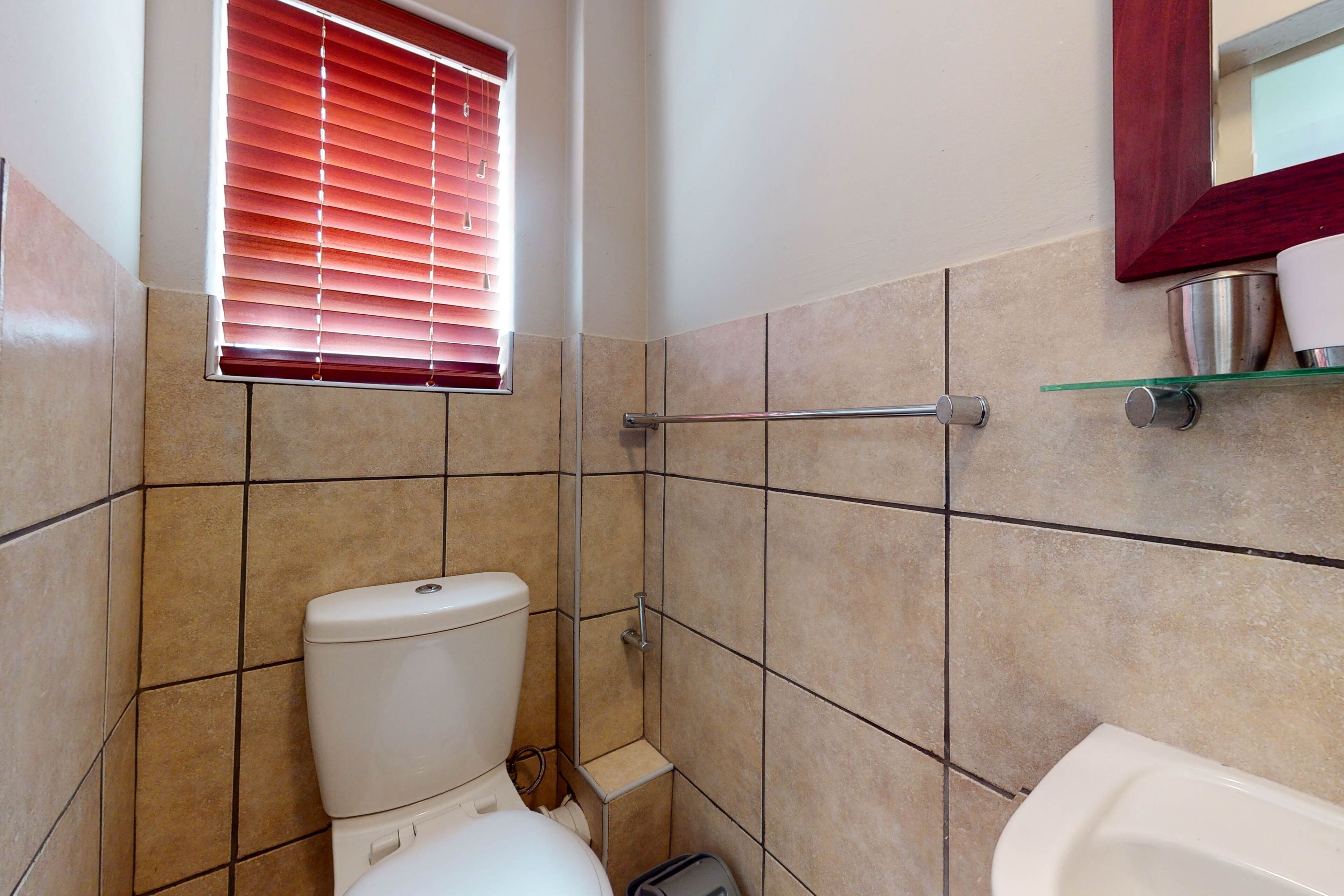 Une petite salle de bain avec des toilettes, une étagère en verre et une baignoire.