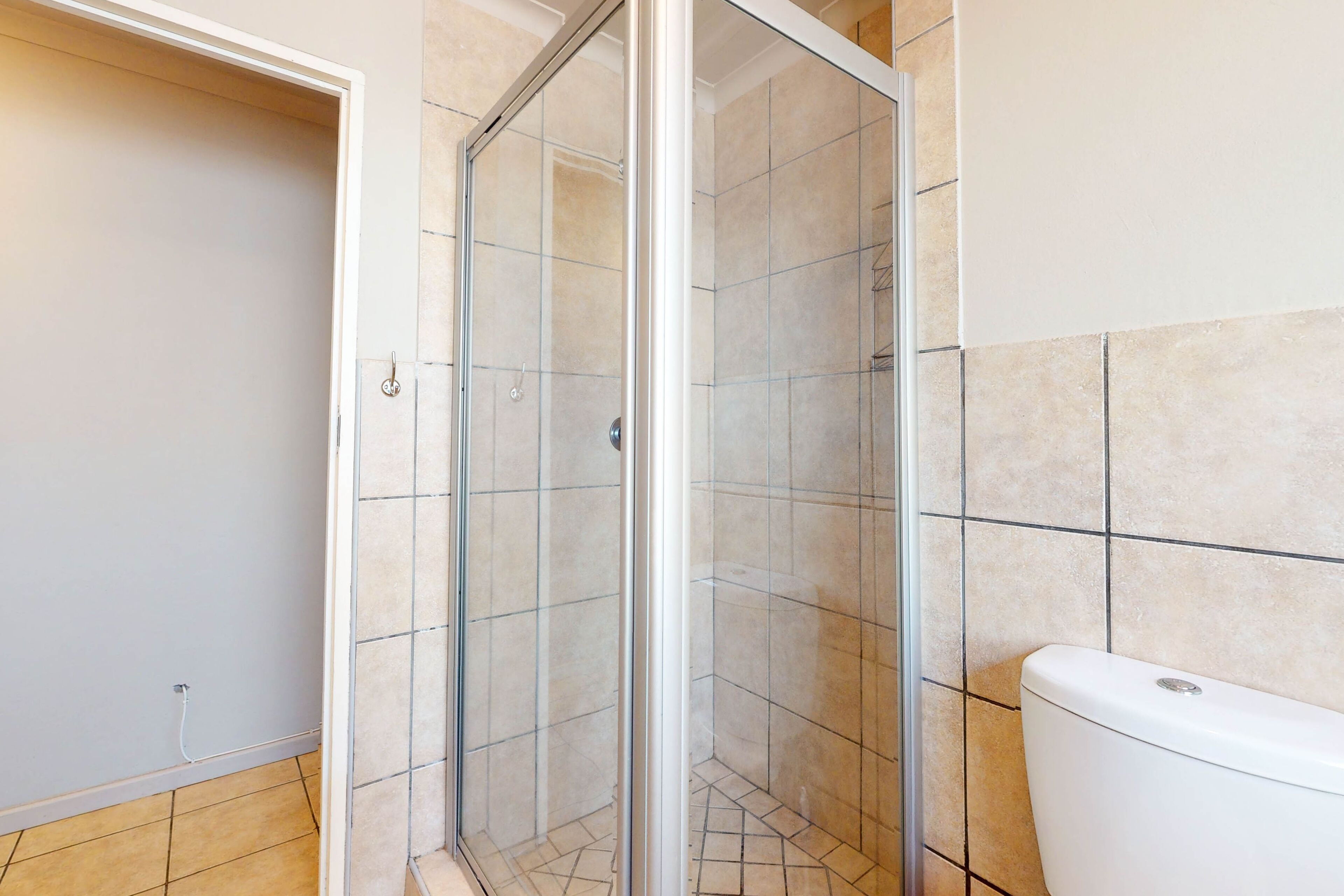Ein Badezimmer mit Duschkabine aus Glas, gefliesten Wänden und Toilette.