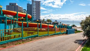 Une zone côtière comprenant un parc aquatique avec des toboggans et une piscine, située à côté d’un hôtel et d’immeubles de grande hauteur.