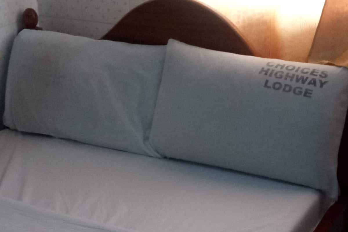 Una cama con ropa de cama y almohadas blancas, una de ellas con texto.