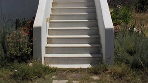 Una escalera que lleva a un edificio blanco, con vistas a montañas y nubes en el fondo.