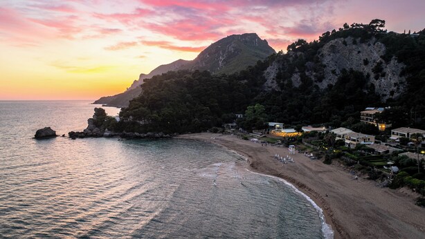 Uma área costeira com praia, falésias rochosas e edifícios iluminados.