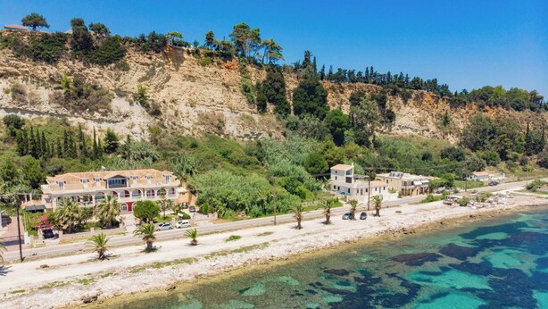 A coastal area with buildings, a beach, and clear blue water. - 'luna Nera' Beachfront Apartment (Zakynthos)