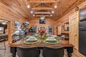A wooden interior with a dining table set for four, surrounded by chairs.