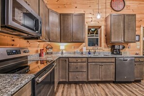 A modern kitchen with granite countertops, stainless steel appliances, and wooden cabinetry.