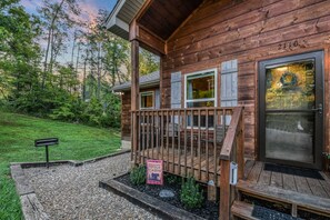 A wooden cabin with a deck, a welcome sign, and a number '2110' on the door.