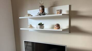 A wall-mounted shelf with decorative items and a television below.