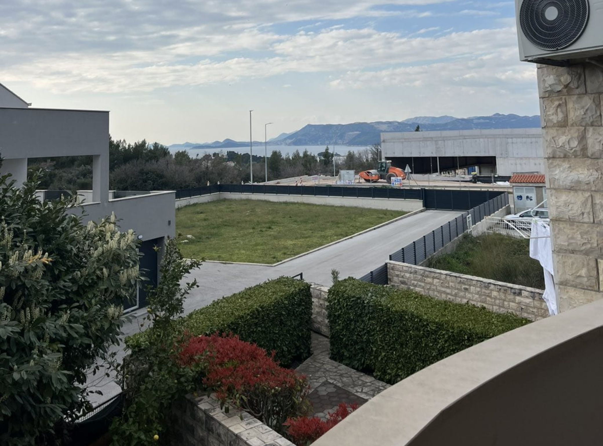 En takterrass med utsikt över bergen, en parkeringsplats och en byggnad som är under uppförande.