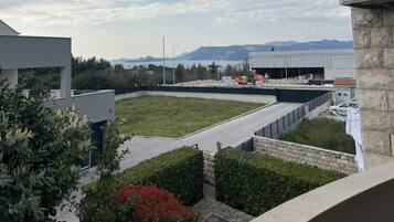 A rooftop with a view of mountains, a parking area, and a building under construction.