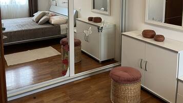A bedroom with a bed, a dresser, a mirror, and a small stool.