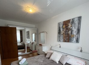 A bedroom with a bed, a bedside table, a mirror, and a large abstract painting on the wall.