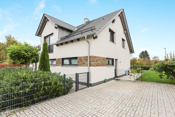 Ein modernes, zweistöckiges Haus mit Ziegelunterbau, einem Ziegeldach und einem gepflasterten Einfahrt.