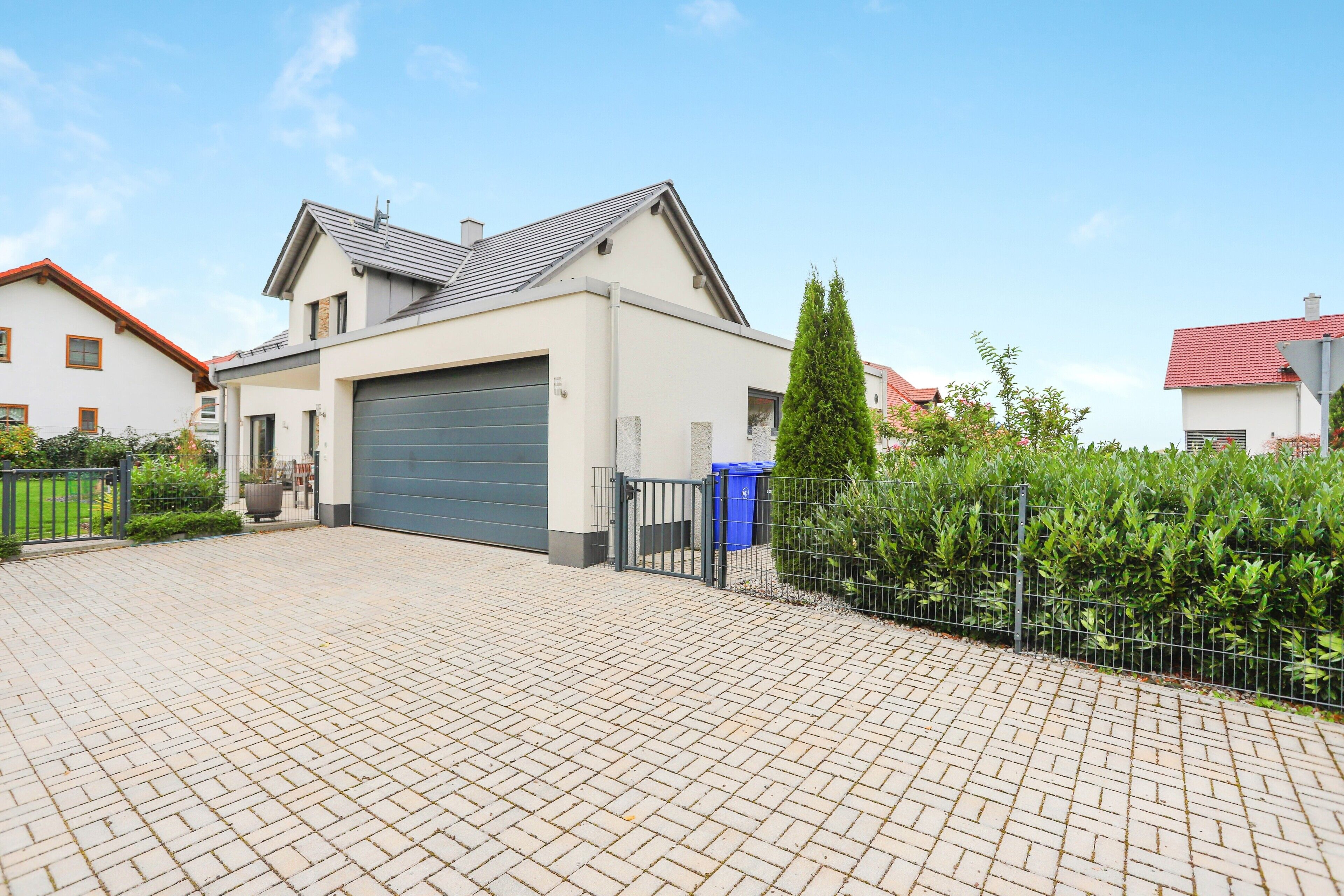 Een modern herenhuis met garage, een verharde oprit en een omheinde tuin.