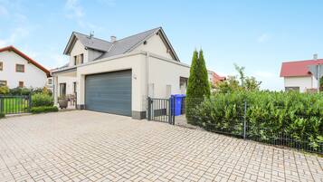 Een modern herenhuis met garage, een verharde oprit en een omheinde tuin.
