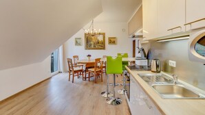 Une cuisine moderne avec un coin repas, un plancher en bois et un lustre.